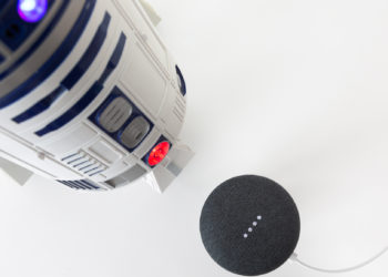 Science fiction meets science fact. Cinematic droid R2-D2 faces off with a Google Home Mini speaker and Google Assistant. Image: Digitized House Media.