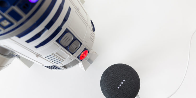 Science fiction meets science fact. Cinematic droid R2-D2 faces off with a Google Home Mini speaker and Google Assistant. Image: Digitized House Media.