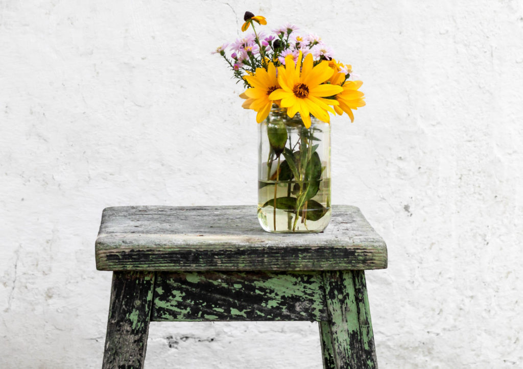 Distressed wood bench, flower vase, yellow and purple flowers. Image: Norwood Themes on Unsplash.